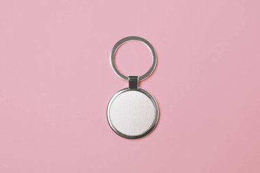 Soluk pembe zemin üzerinde gümüş anahtarlık, üst görünüm