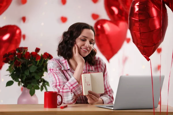 Valentine\'s day celebration in long distance relationship. Woman having video chat with her boyfriend via laptop indoors