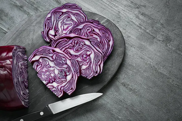 Slices of fresh ripe red cabbage and knife on grey table, flat lay. Space for text