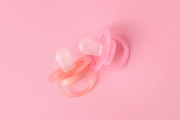 New baby pacifiers on pink background, flat lay