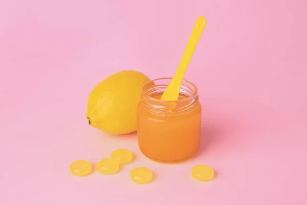 Cough drops, fresh orange and honey on pink background
