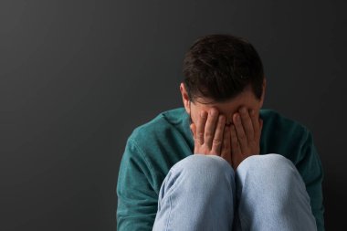 Siyah arka planda oturan üzgün adam. Metin için boşluk