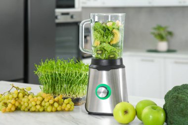 Smoothie için malzemelerle karıştırıcı ve mutfak beyaz mermer masa üzerinde ürünler
