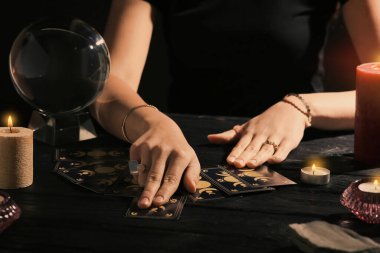 Kahin, karanlıkta tarot kartlarıyla geleceği tahmin ediyor. Yakın plan.