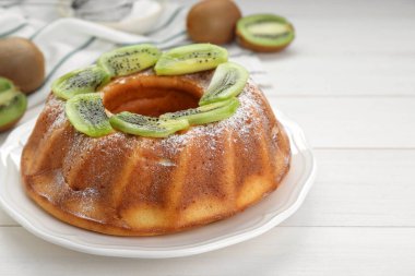 Homemade yogurt cake with kiwi and powdered sugar on white wooden table
