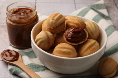 Delicious nut shaped cookies with boiled condensed milk on table, closeup