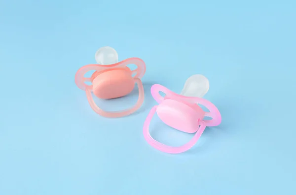 Two new baby pacifiers on light blue background