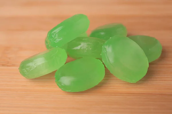 Many light green cough drops on wooden table, closeup