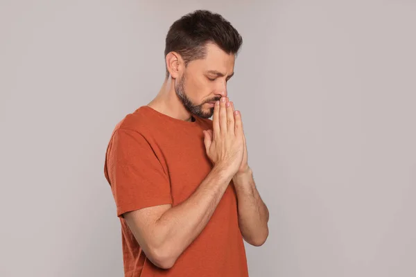 Elleri Sıkıca Bağlı Açık Gri Arka Planda Dua Eden Adam — Stok fotoğraf