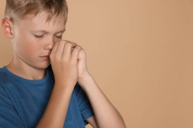 Elleri sımsıkı bağlı bej arka planda dua eden çocuk, metin için boşluk