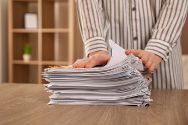 Woman stacking documents at wooden table indoors, closeup clipart