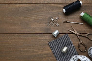 Düz kompozisyon, yüksükler ve farklı dikiş aletleriyle ahşap masa üzerinde yatıyordu. Metin için boşluk