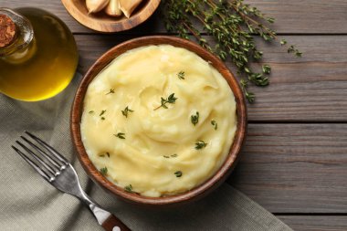 Delicious mashed potato with thyme served on wooden table, flat lay