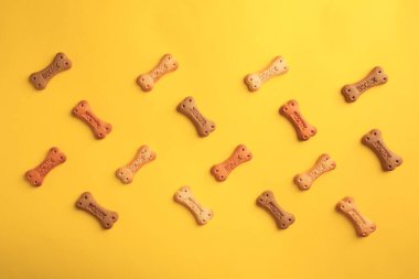 Bone shaped dog cookies on yellow background, flat lay