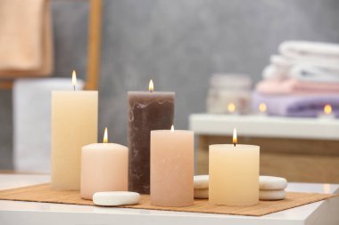 Beautiful spa composition with burning candles and stones on white table in wellness center