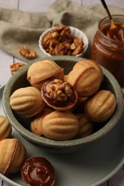 Delicious nut shaped cookies with boiled condensed milk on table, closeup