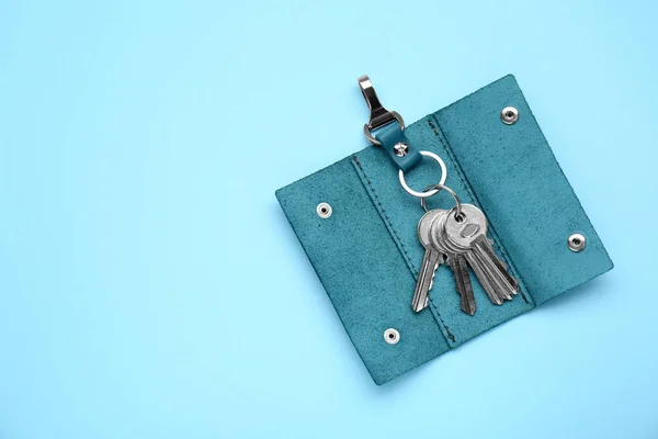 Leather holder with keys on light blue background, top view. Space for text