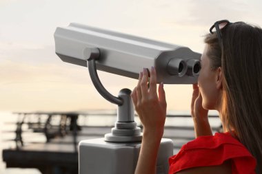Genç kadın gözlem güvertesindeki turist izleme makinesine bakıyor.