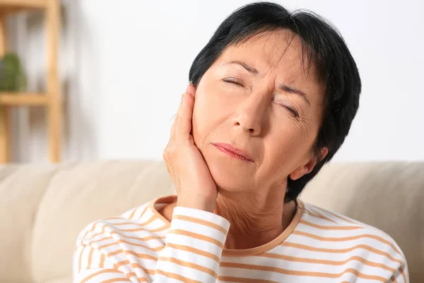 Senior woman suffering from ear pain at home
