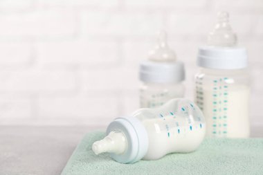 Açık gri masada bebek mamasıyla beslenme şişeleri. Metin için boşluk