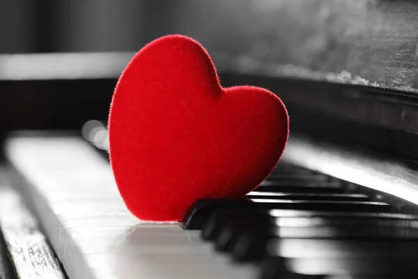 Small red decorative heart on piano keys, closeup