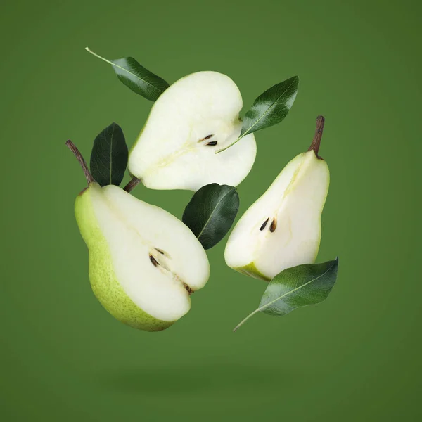 Fresh ripe cut pears and leaves falling on green background