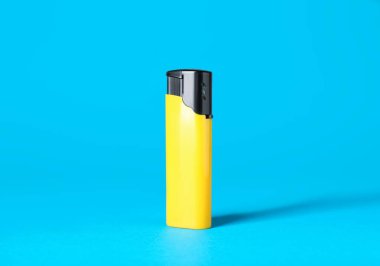 Yellow plastic cigarette lighter on light blue background