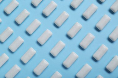 Açık mavi arkaplanda beyaz sakız çiğniyor.