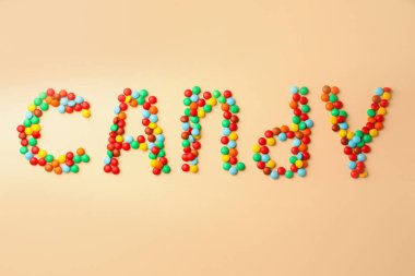 Word Candy made of tasty sweets on beige background, flat lay