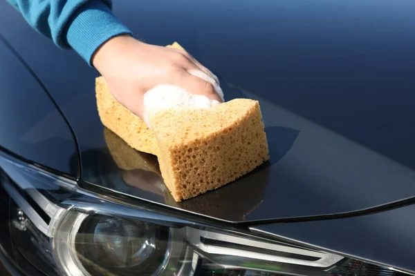 Man washing car hood with sponge, closeup
