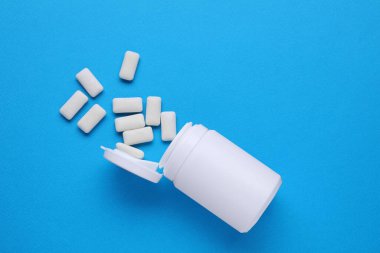 Açık mavi zemin üzerinde sakız çiğneyen kavanoz, düz yatıyordu