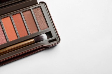 Beautiful eye shadow palette with brush on white table, top view. Space for text