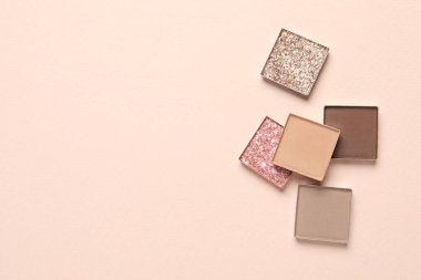 Different beautiful eye shadows on beige background, flat lay. Space for text