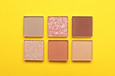Beautiful eye shadow refill pans on yellow background, flat lay