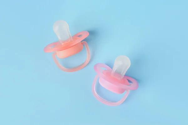 New baby pacifiers on light blue background, flat lay