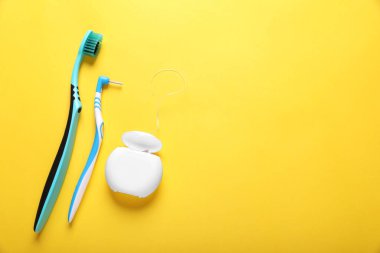 Flat lay composition with dental floss and different teeth care products on yellow background. Space for text