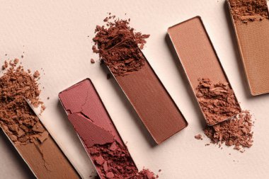 Different crushed eye shadows on beige background, flat lay