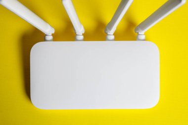New white Wi-Fi router on yellow background, top view