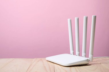New Wi-Fi router on wooden table against pink background. Space for text