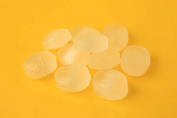 Many cough drops on orange background, closeup