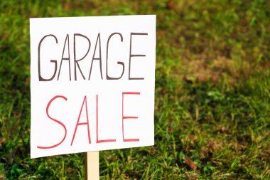 Sign Garage sale written on cardboard near grass, closeup. Space for text