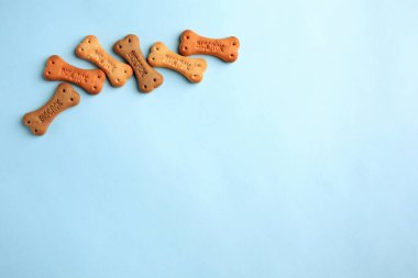 Bone shaped dog cookies on light blue background, flat lay. Space for text