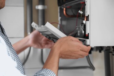 Man opening top of gas boiler indoors, closeup