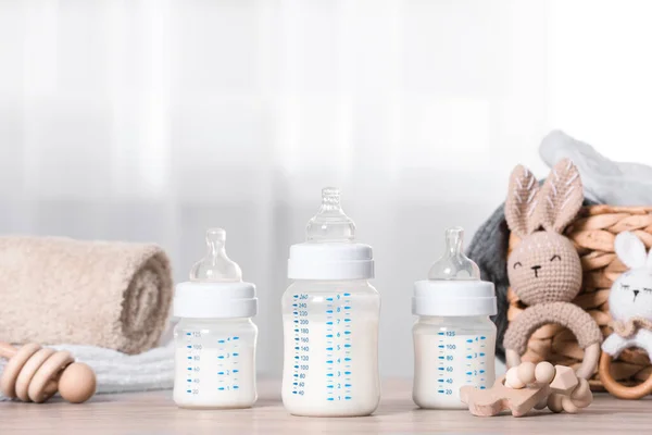 Feeding bottles with milk and baby accessories on wooden table indoors