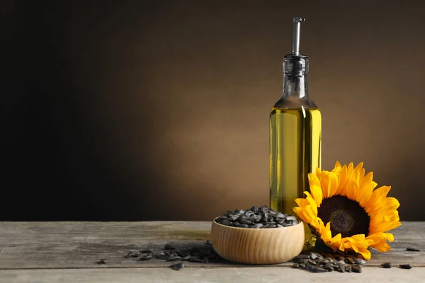 Sunflower cooking oil, seeds and yellow flower on light grey table, space for text