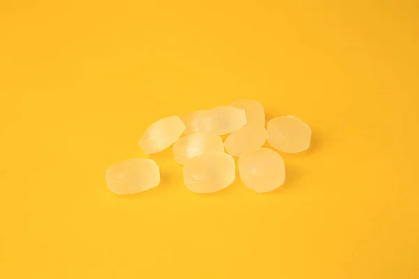 Many yellow cough drops on orange background