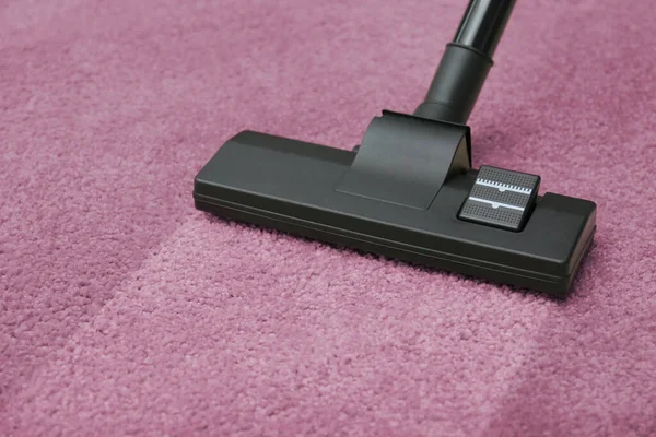 Vacuuming dirty pink carpet. Clean area after using device, closeup