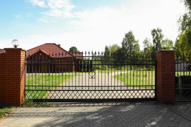 Closed metal gates near houses and trees
