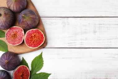 Fresh ripe purple figs on white wooden table, flat lay. Space for text