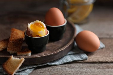 Soft boiled chicken eggs with toasted bread on wooden table